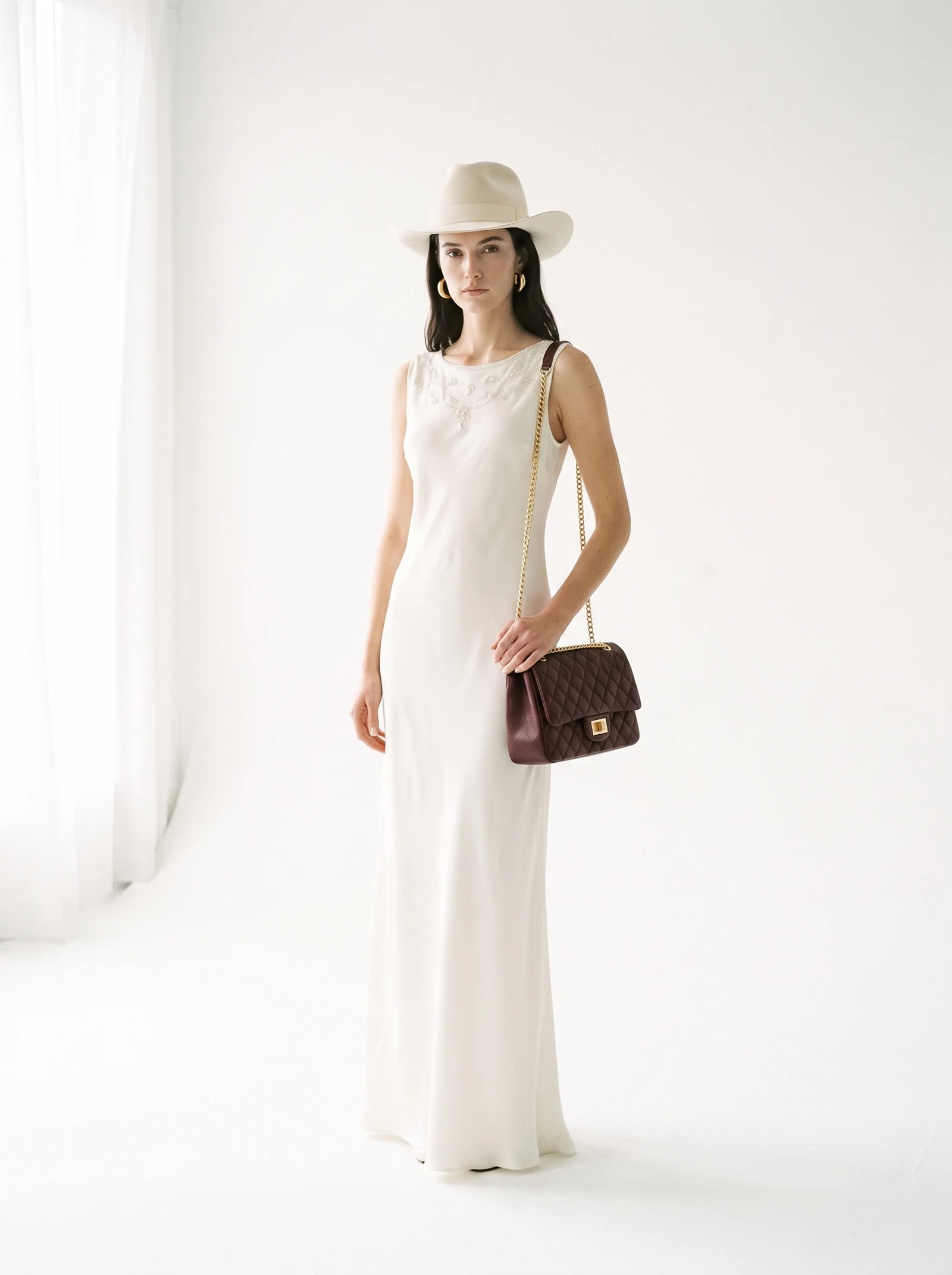 L'abito, il cappello, gli orecchini e la borsa arrivano come quattro packshot separati, mai stati nella stessa stanza. Tornano indietro come un unico look, su una sola modella, in un solo scatto.